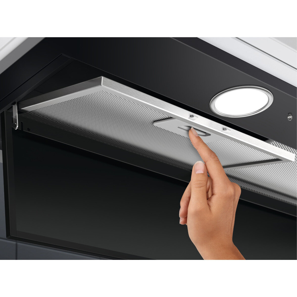 Ręka dotykająca metalowego filtra wewnątrz czarnego okapu.