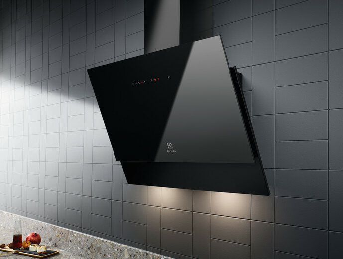 Czarny okap kuchenny zamontowany na kafelkowej ścianie. Światła są włączone. Design jest elegancki i nowoczesny.