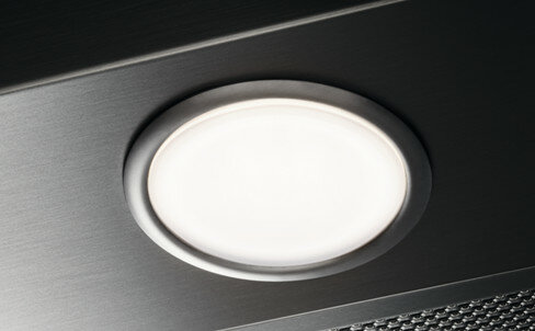 Zbliżenie owalnego światła w okapie kuchennym, tło z metalową powierzchnią.