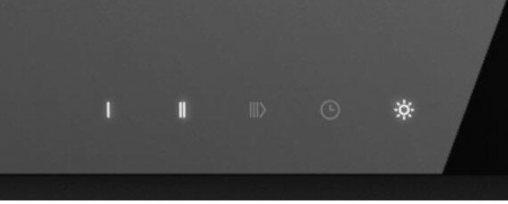 Zbliżenie panelu sterowania z podświetlonymi ikonami na ciemnym tle.