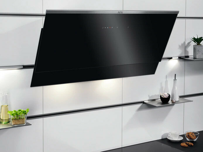 Nowoczesna scena kuchenna, czarny okap, białe szafki i elementy dekoracyjne.