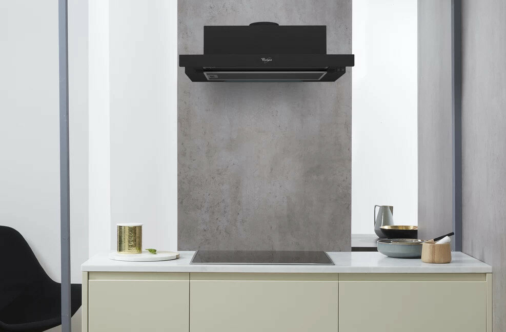 Czarny okap Whirlpool zamontowany nad kuchenką, z blatem i szafkami.