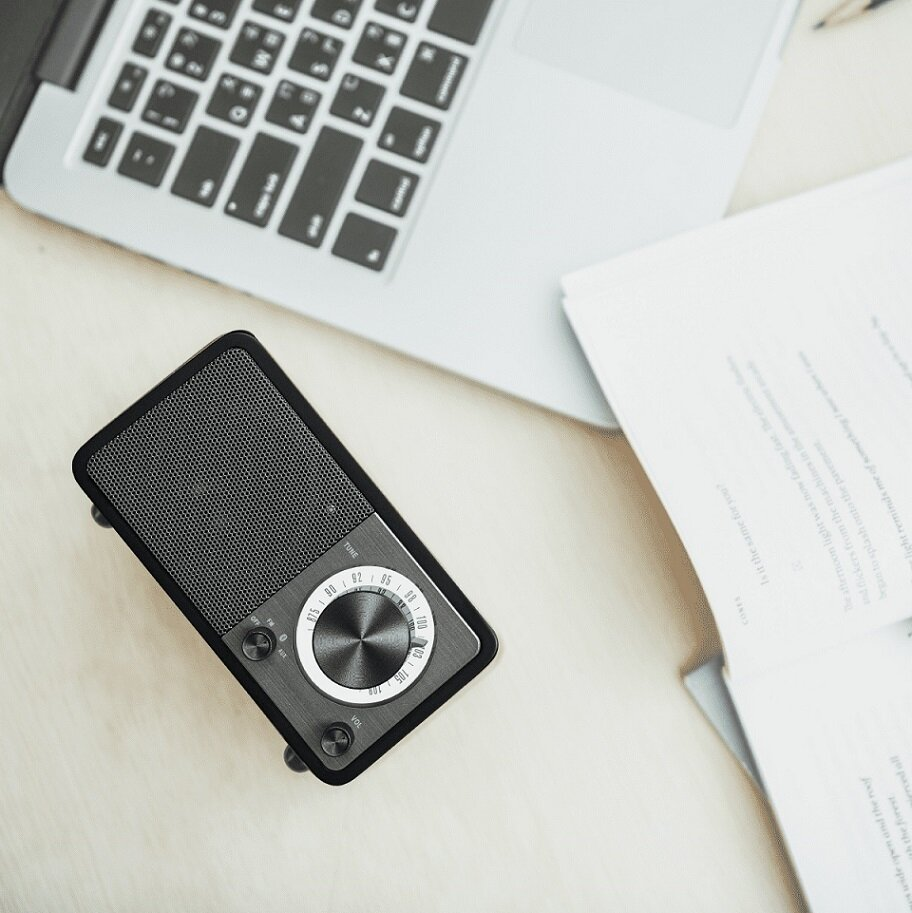 Radio, laptop i kilka kartek na drewnianym stole.