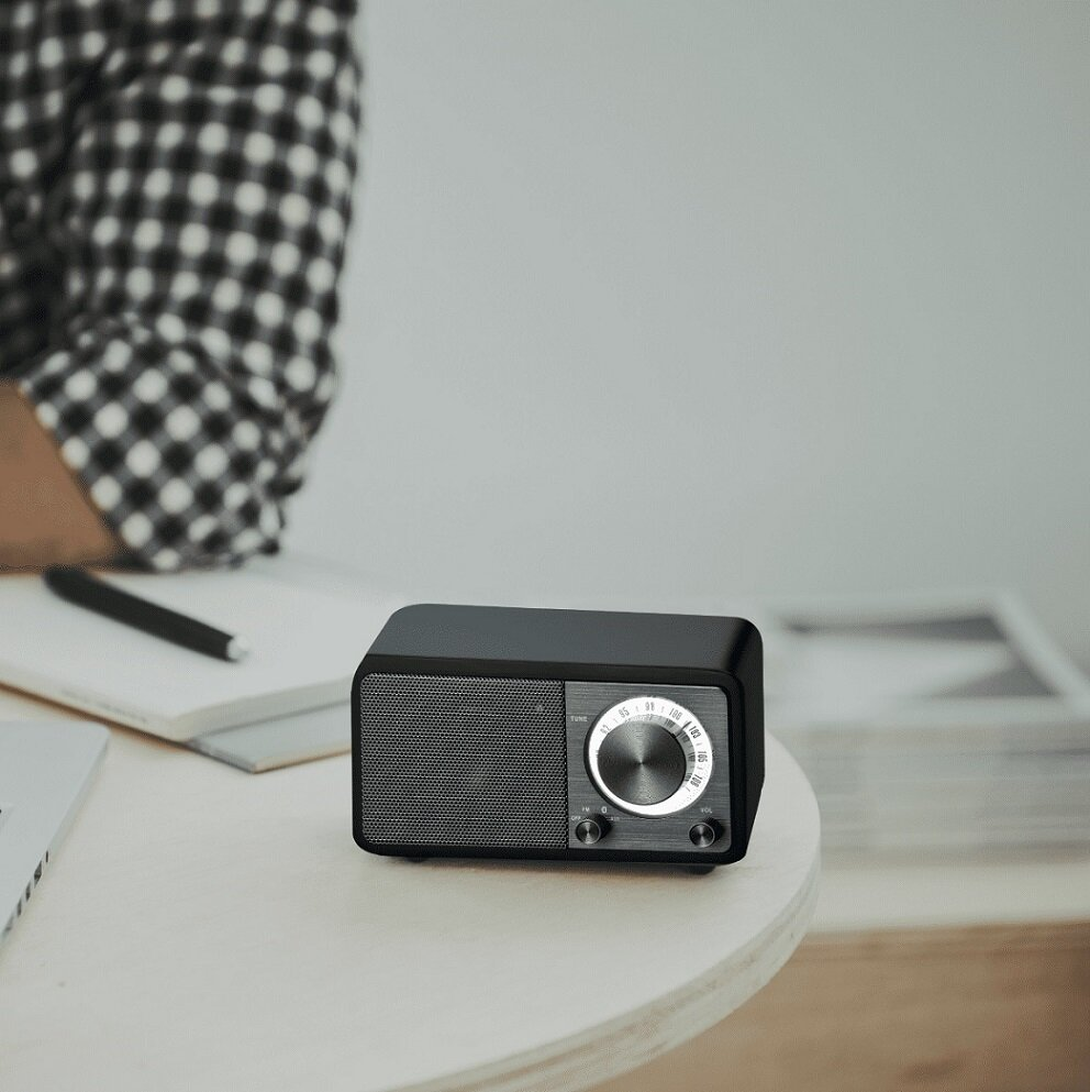 Czarne radio retro z osobą w koszuli w kratę w tle.