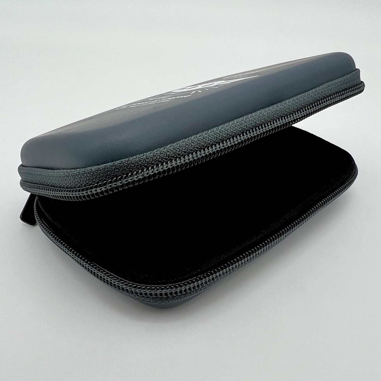 Estuche gris abierto con cremallera y interior negro, sobre superficie blanca.
