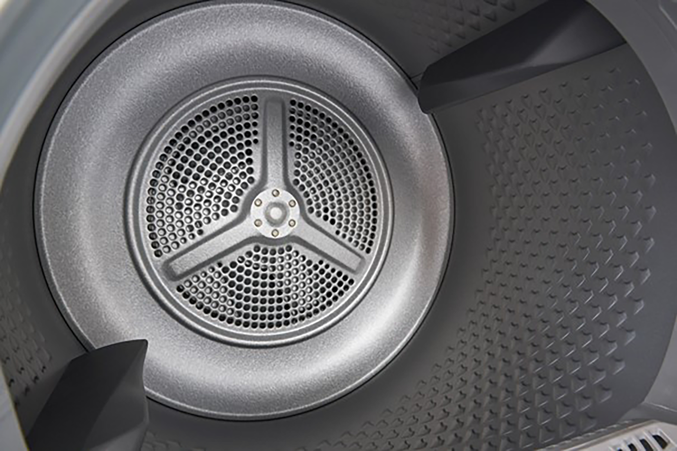 Binnenkant van een droogtrommel. Een ronde metalen plaat met gaten en een ventilator met drie bladen is zichtbaar.