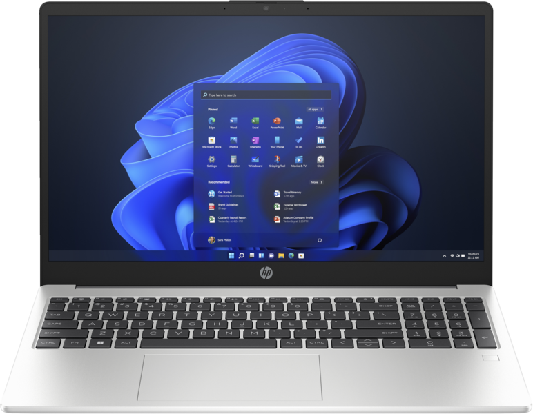 Ezüst laptop fehér felületen. A képernyő Windows 11 felületet jelenít meg alkalmazásikonokkal. Fekete billentyűzet.