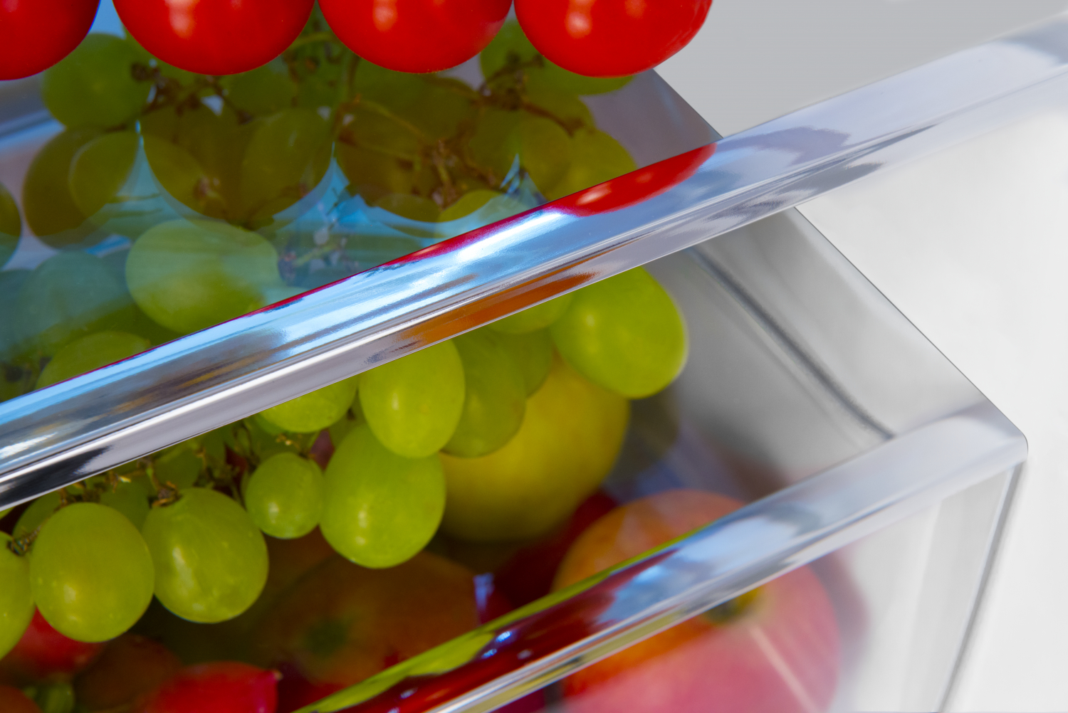 Nahaufnahme von Trauben und Tomaten in einer Kühlschublade.