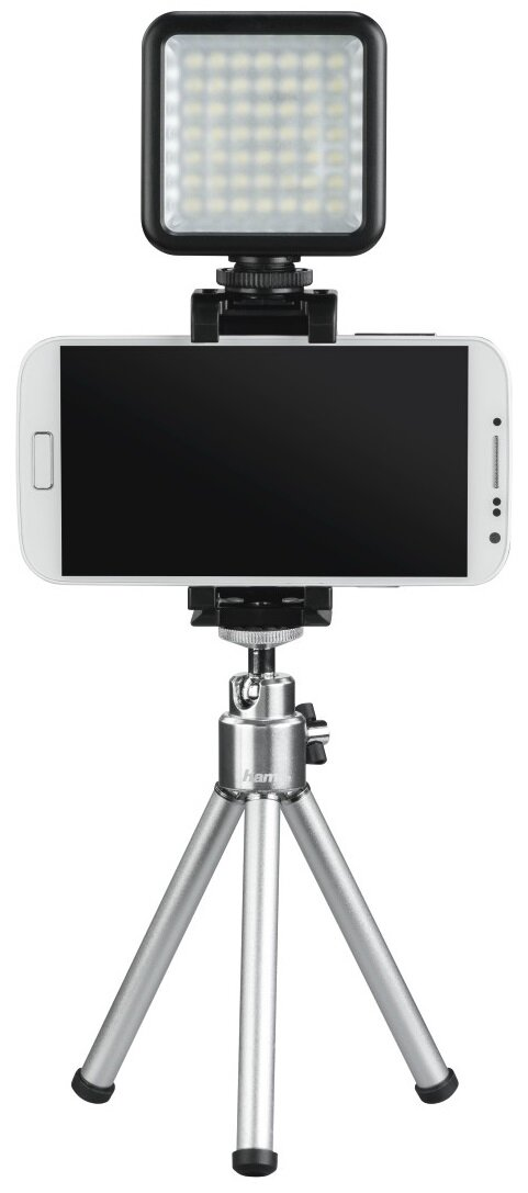 Smartfon na statywie z lampą u góry, wszystko na białym tle.