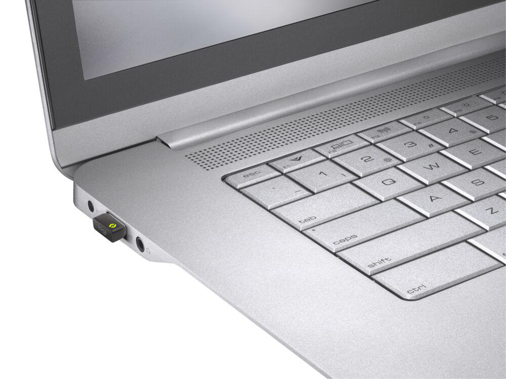 Ein silberner Laptop mit einem kleinen USB-Dongle, der an der Seite eingesteckt ist. Der Dongle ist grün.