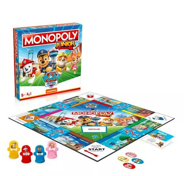 Pudełko i plansza gry Monopoly Junior z postaciami z Psiego Patrolu. Figurki w zestawie. Białe tło.