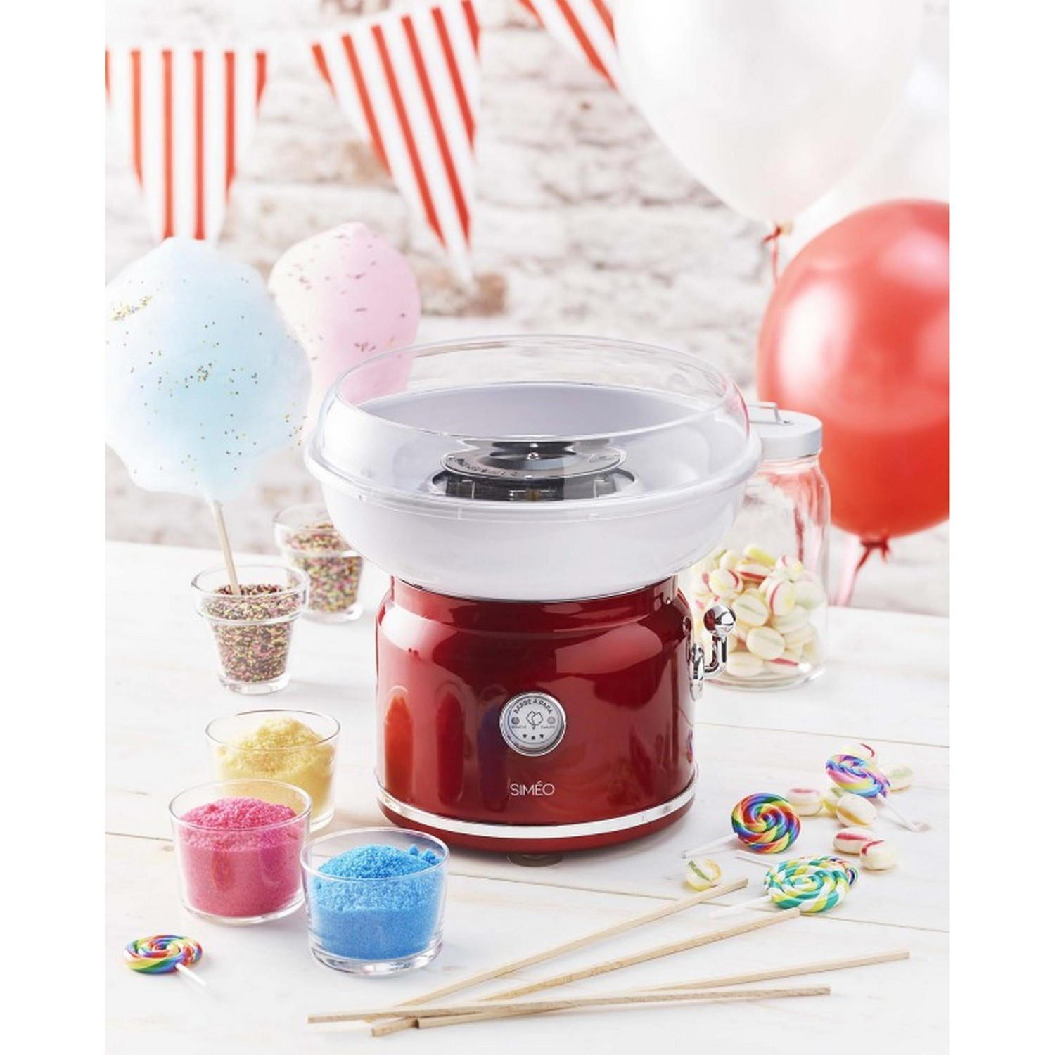 Suikerspinmachine met snoep en lolly's op een tafel.