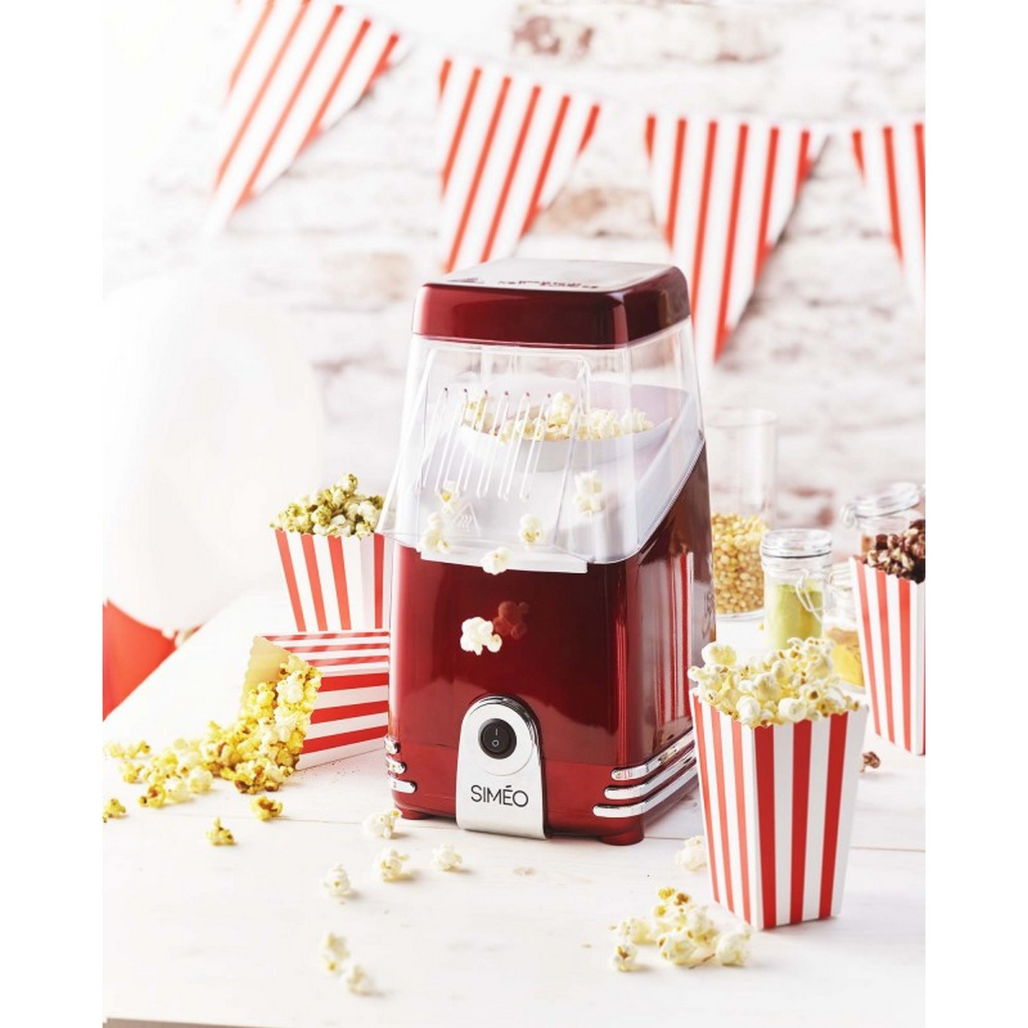 A red popcorn maker with popcorn in cups and containers.