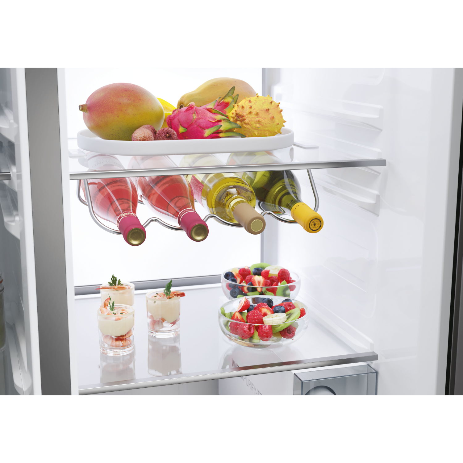 Fridge interior with fruit plates, wine bottles, and small appetizers arranged on shelves.