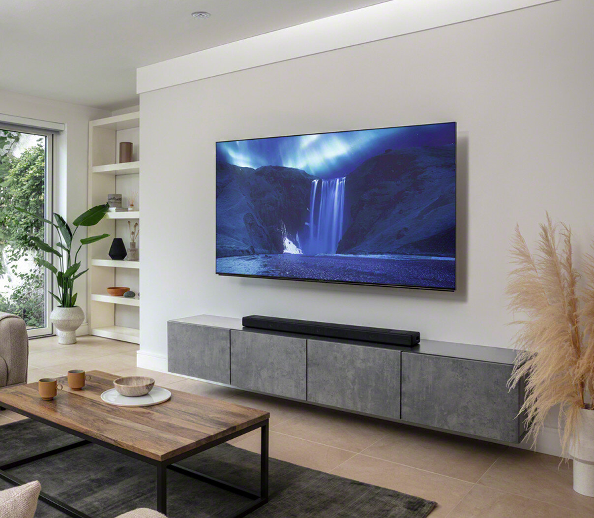 Salon z telewizorem na ścianie, soundbarem poniżej i stolikiem kawowym.