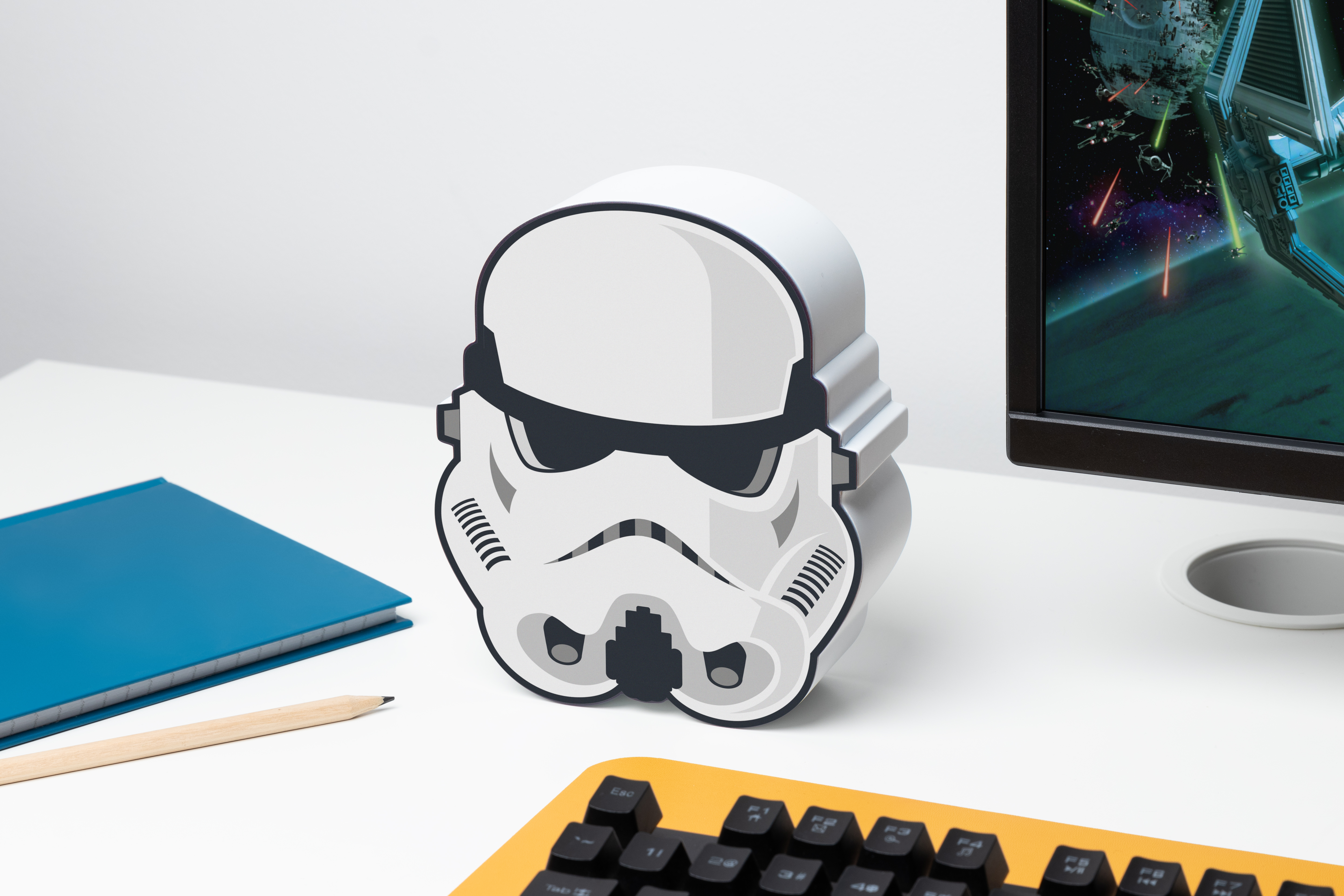Sturmtruppenhelm-Lautsprecher auf weißem Schreibtisch mit Tastatur und Monitor.