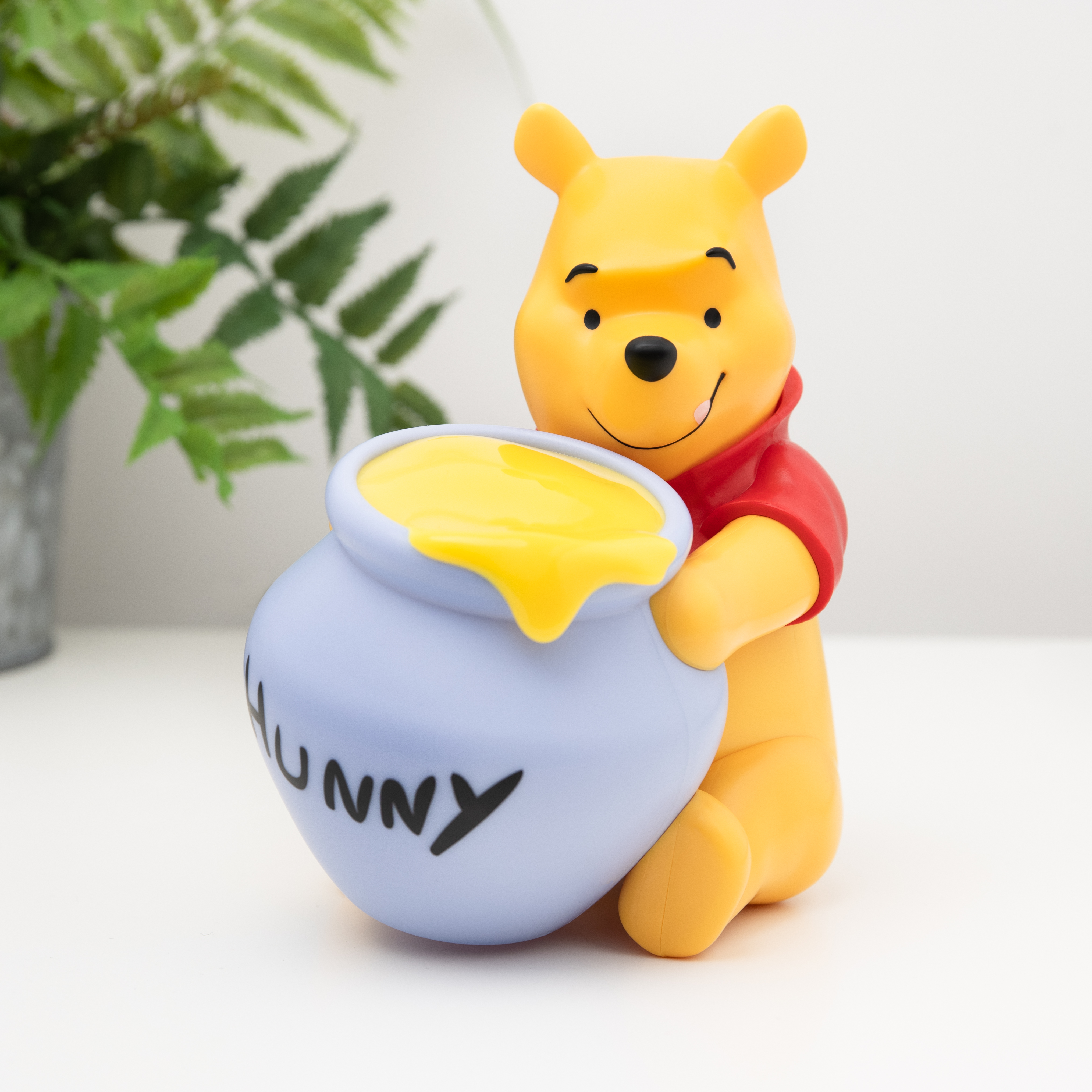 Winnie-the-Pooh-Figur mit einem Honigtopf. Weißer Hintergrund.