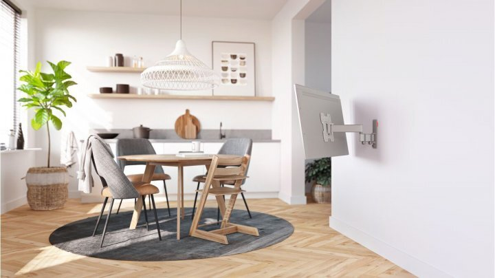 Jasna jadalnia ze stołem, krzesłami, roślinami i uchwytem TV na ścianie.