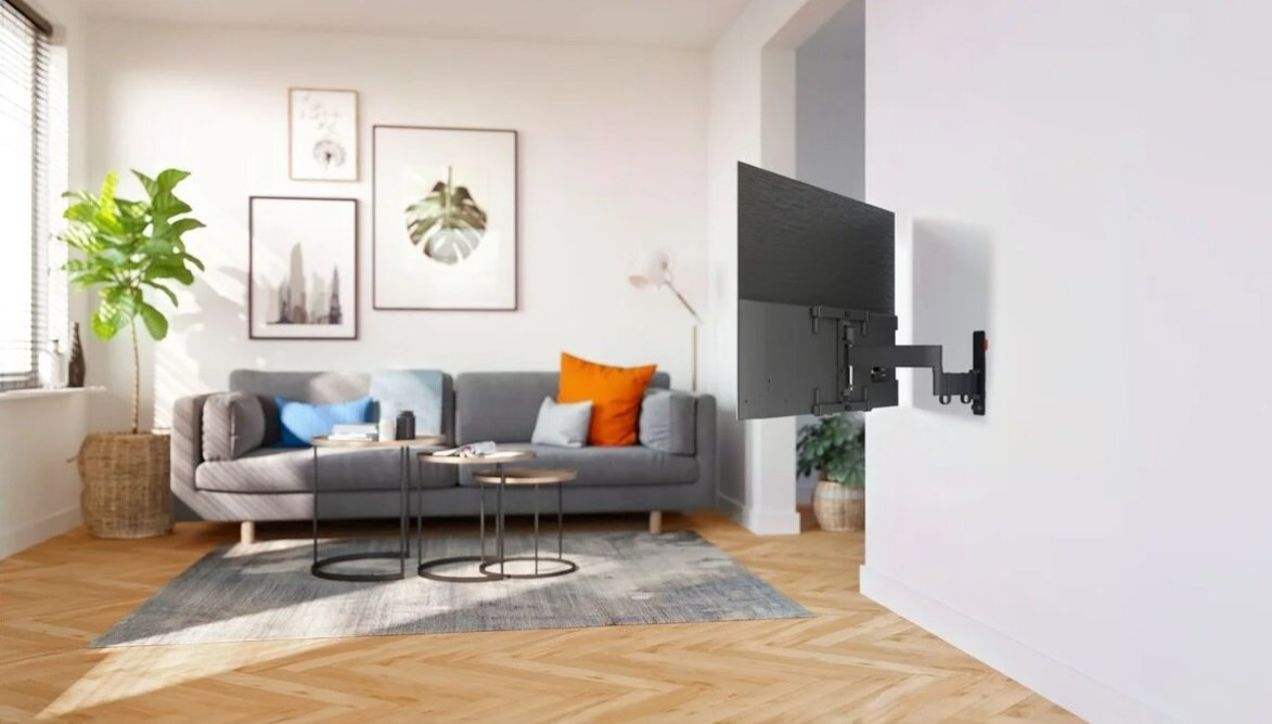 Salon z szarą sofą, telewizorem na ścianie i grafikami. Stoliki kawowe i dywan.