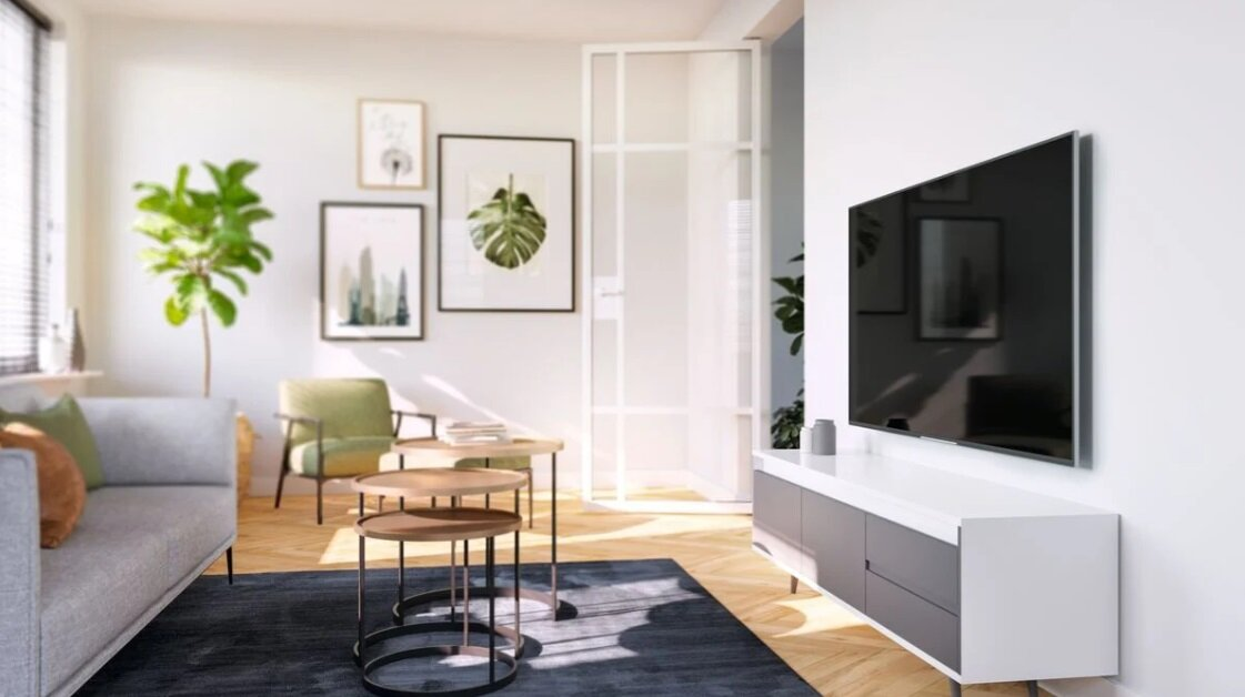 Nowoczesny salon, z telewizorem na ścianie, sofą i stolikami kawowymi. Drewniana podłoga.