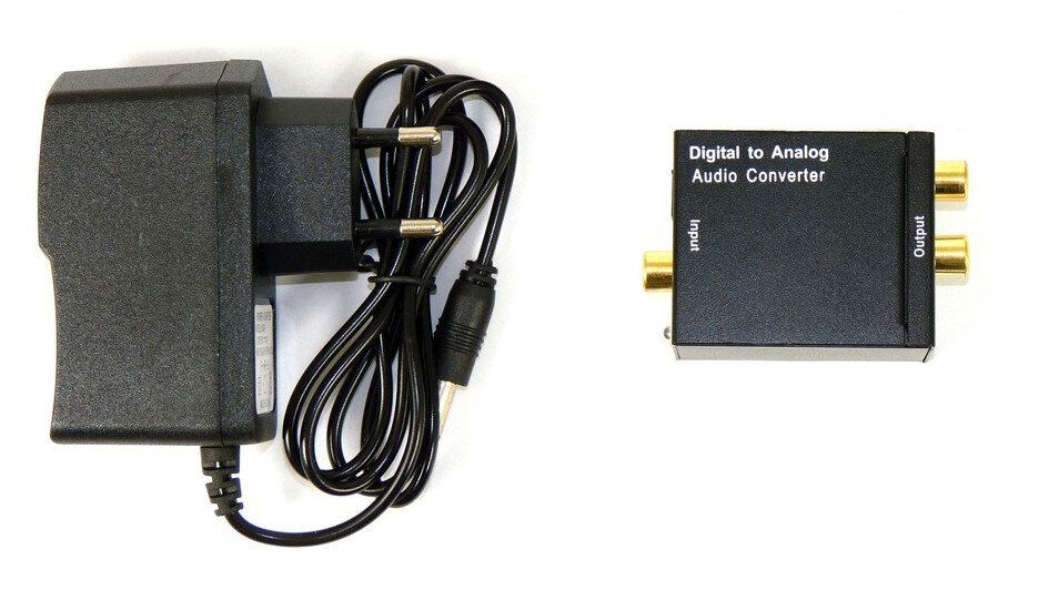 Czarny zasilacz, kabel i konwerter audio cyfrowo-analogowy na białej powierzchni.