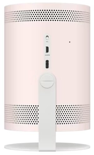 Tył jasnoróżowego głośnika cylindrycznego z otworami wentylacyjnymi i portami, na białej podstawie.