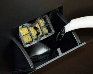 Zbliżenie czarnego pojemnika z filtrem, który jest czyszczony wodą.