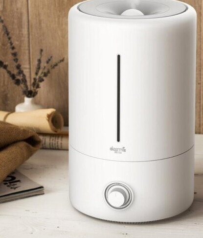 Biały nawilżacz z czarną linią. W tle rośliny i książki. To nowoczesny design.