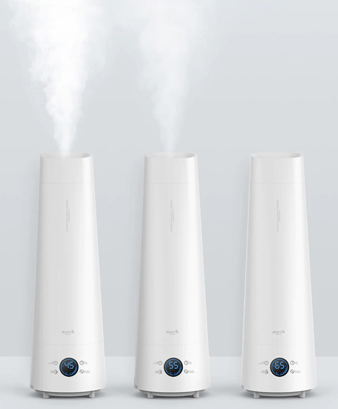 Trzy białe nawilżacze powietrza emitujące parę. Każdy ma cyfrowy wyświetlacz z temperaturami: 45, 55 i 65. Tło jest białe.
