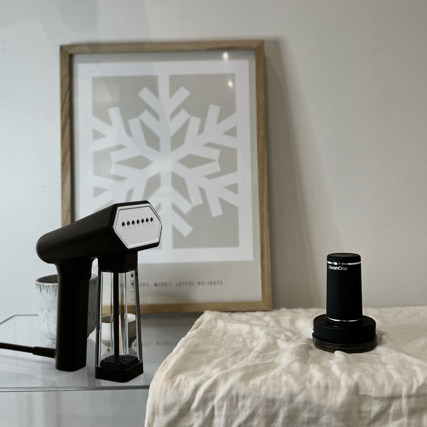 Un défroisseur noir et un appareil de chargement sur une table blanche avec un cadre photo en arrière-plan.