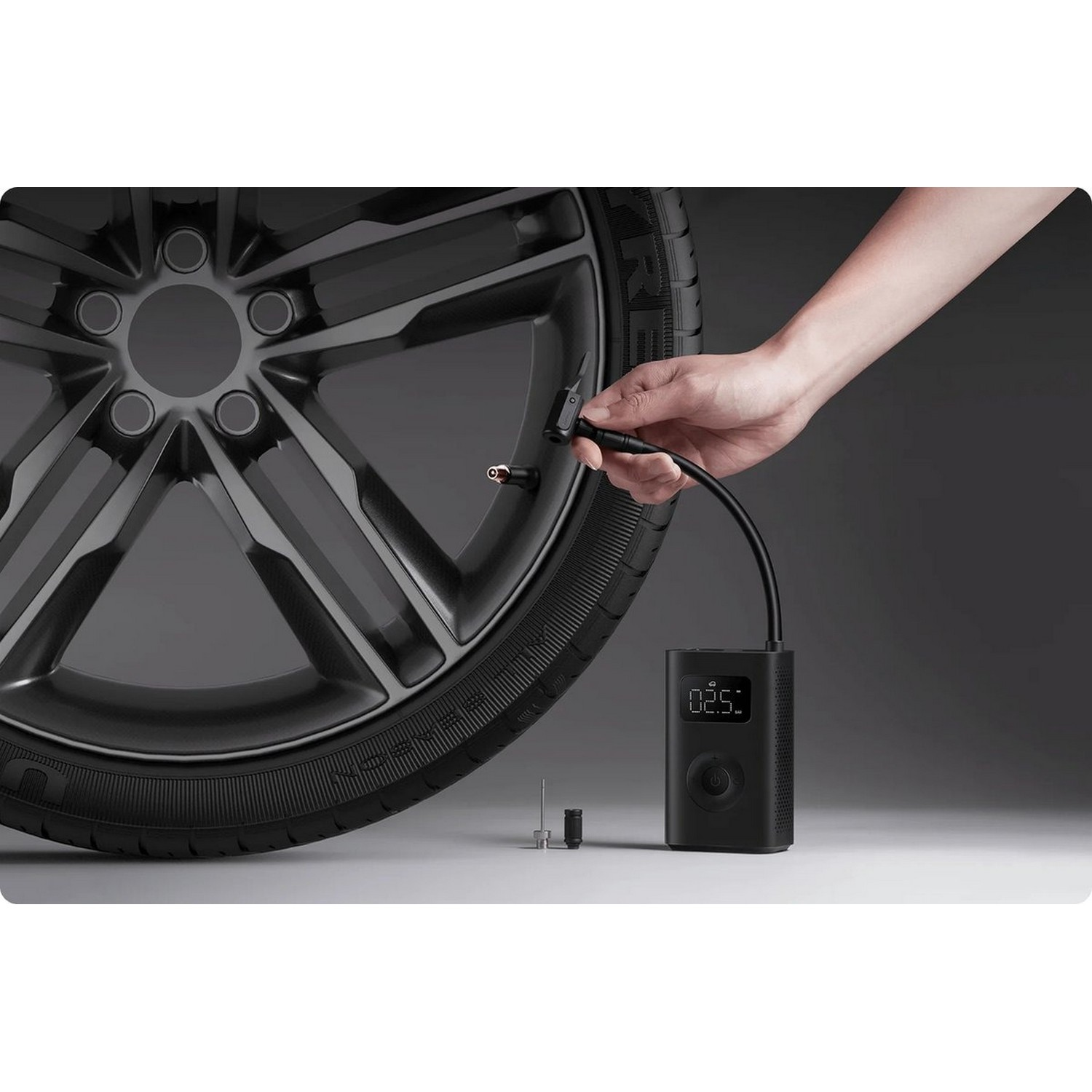 Gonfleur de pneu noir avec un tuyau noir connecté à un pneu de voiture.