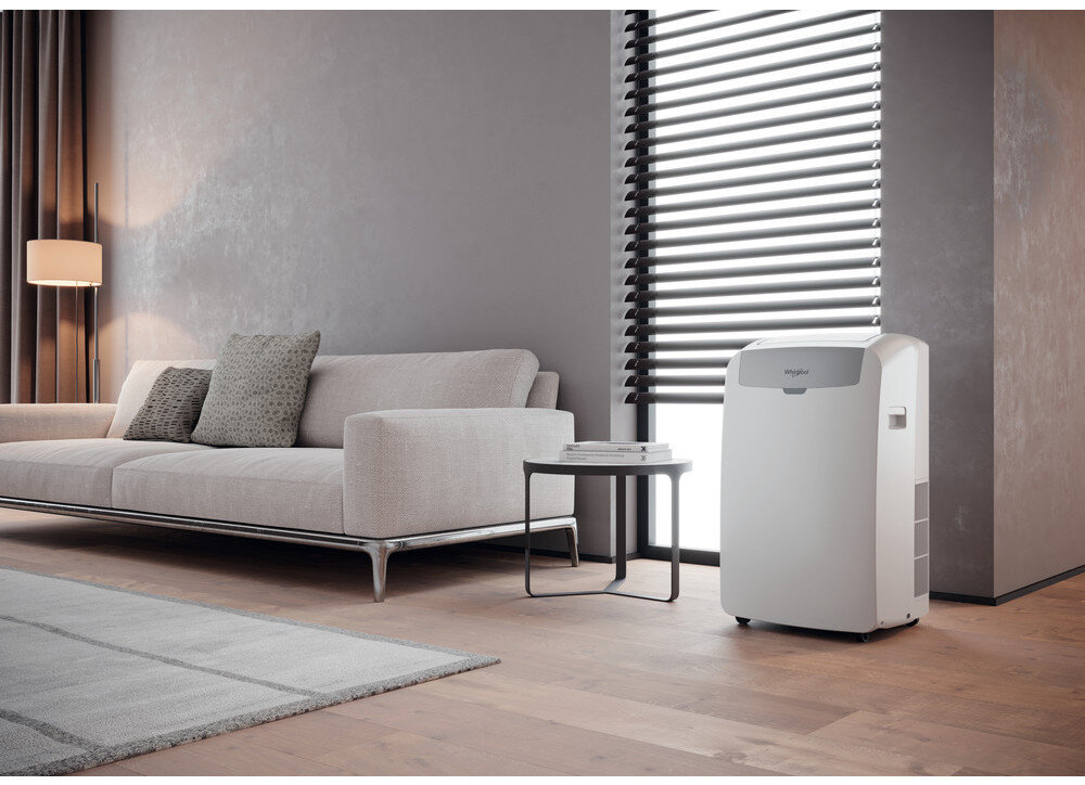 Salon z sofą, stolikiem i klimatyzatorem. Szare ściany, jasny dywan i lampa podłogowa.