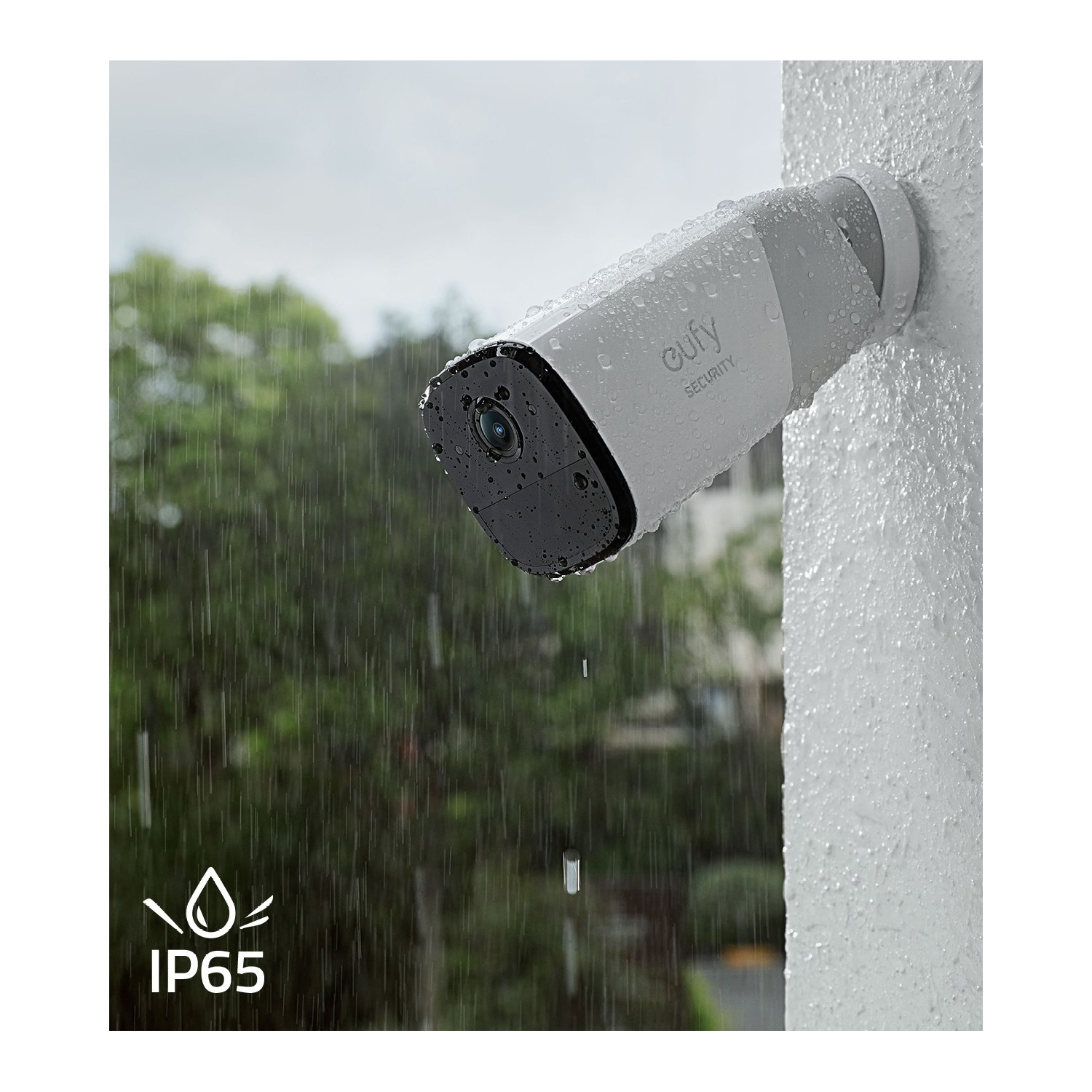 Caméra de sécurité blanche sur un mur sous la pluie. Elle a un objectif noir et est fixée au mur.