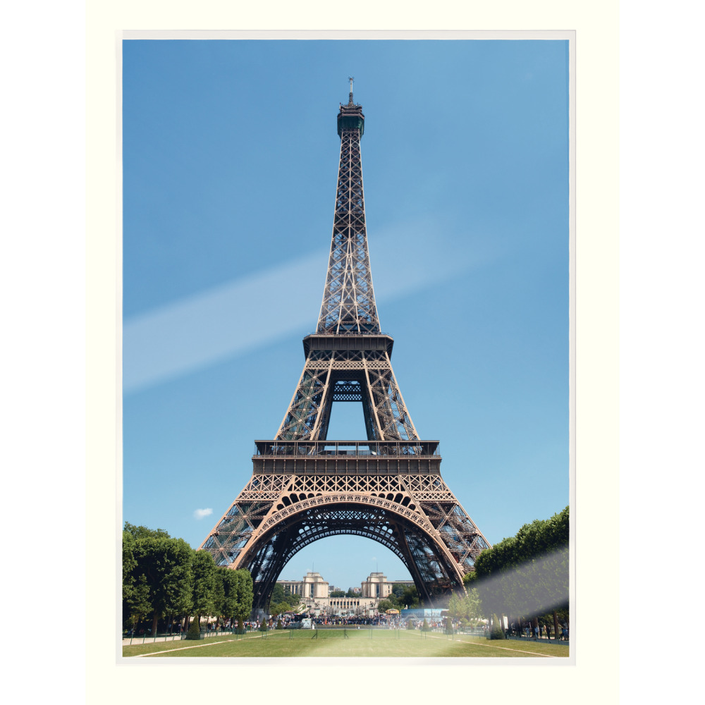 Eiffel-torony Párizsban kék ég alatt zöld fákkal és emberekkel.