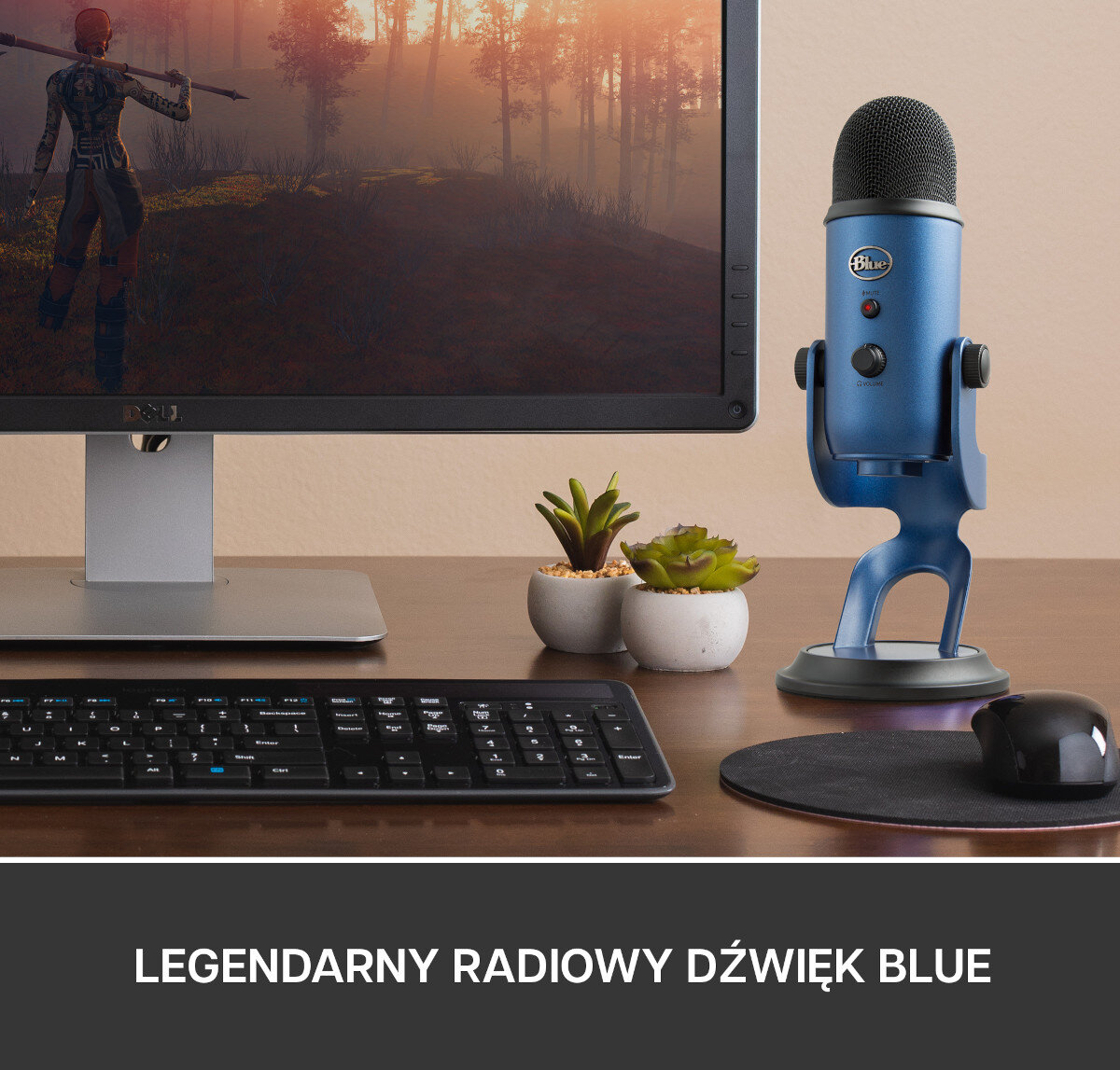 Biurko z monitorem, klawiaturą i myszą. Niebieski mikrofon umieszczony jest po prawej stronie.
