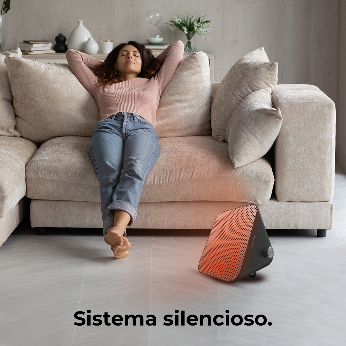 Mujer relajándose en un sofá cerca de un calefactor negro. Texto: Sistema silencioso.