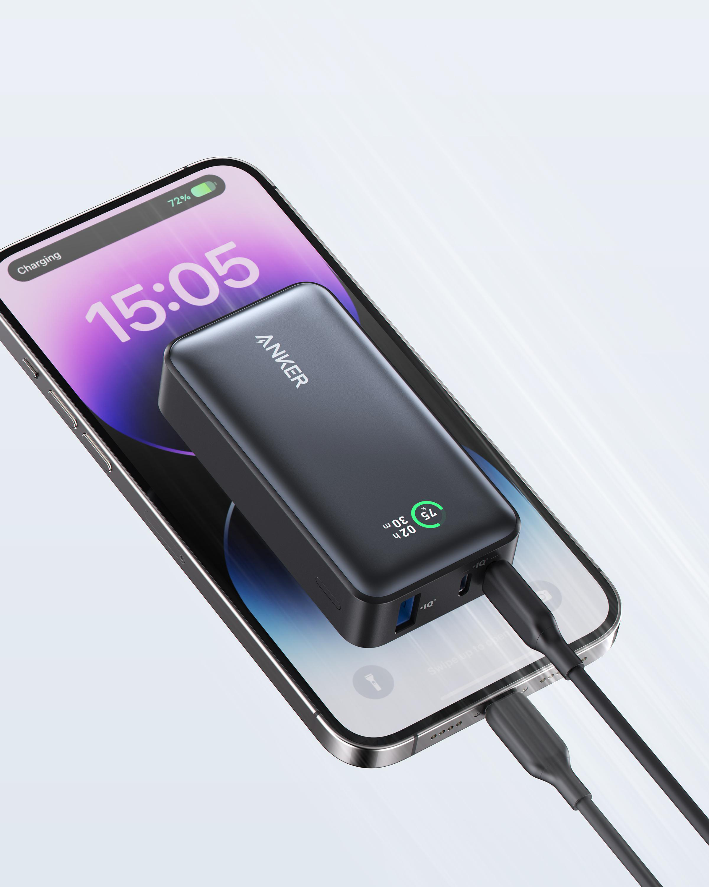 Schwarze Anker Powerbank, die ein Telefon lädt. Schwarzes Kabel eingesteckt.