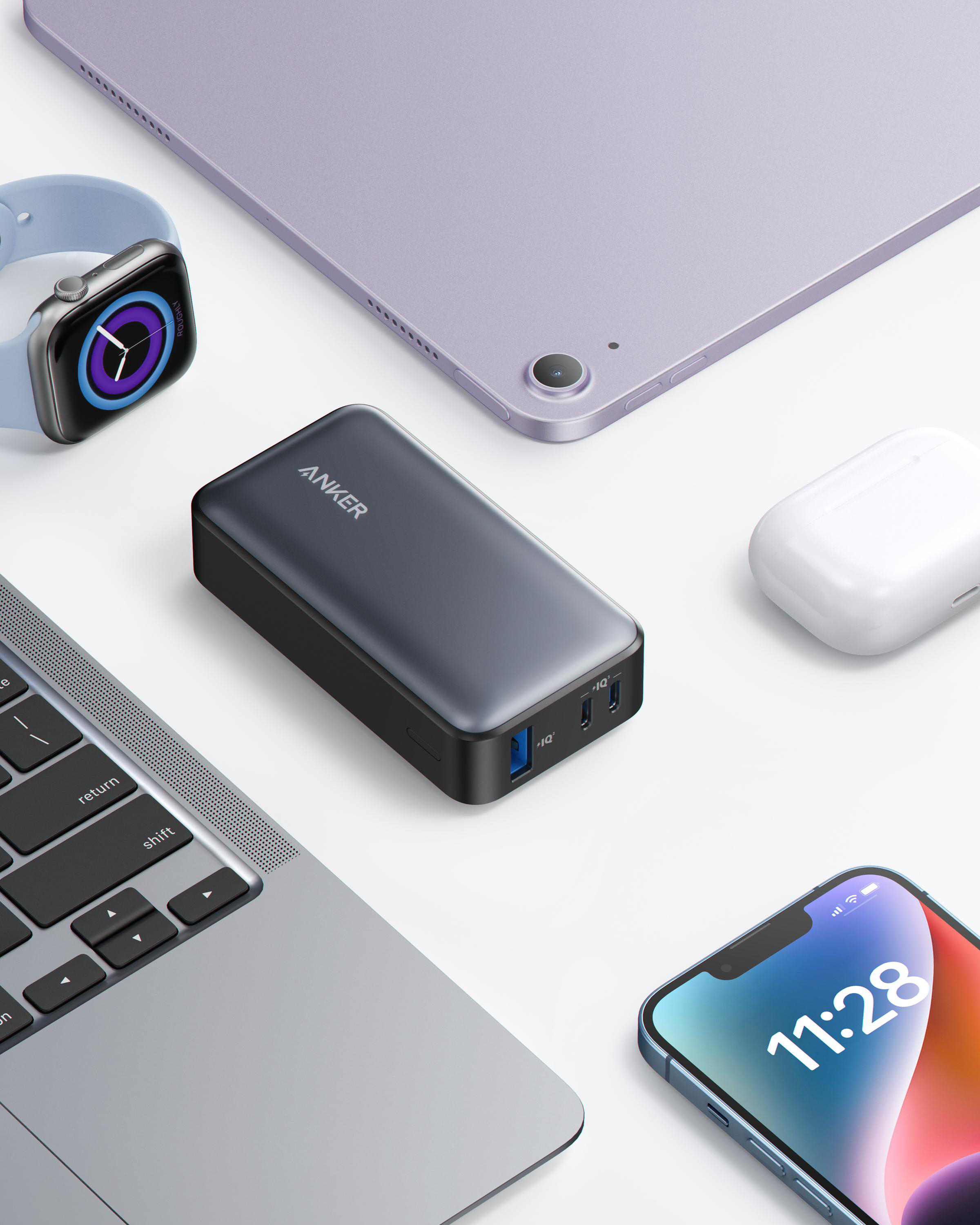 Anker Powerbank mit Apple-Geräten, Laptop, Uhr, Telefon, alles auf weißer Oberfläche.