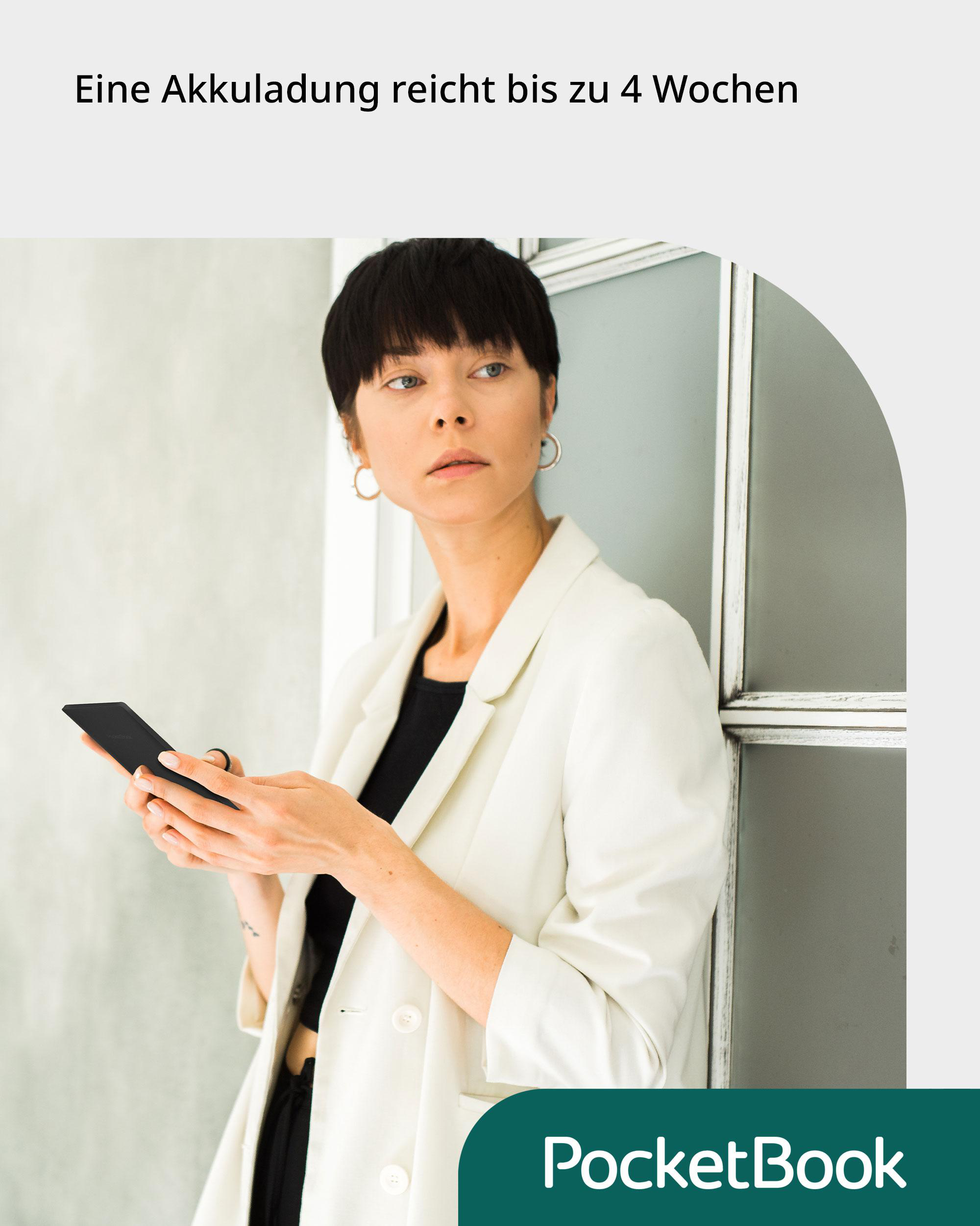 Frau in weißem Mantel hält einen schwarzen E-Reader, lehnt an einer Wand.