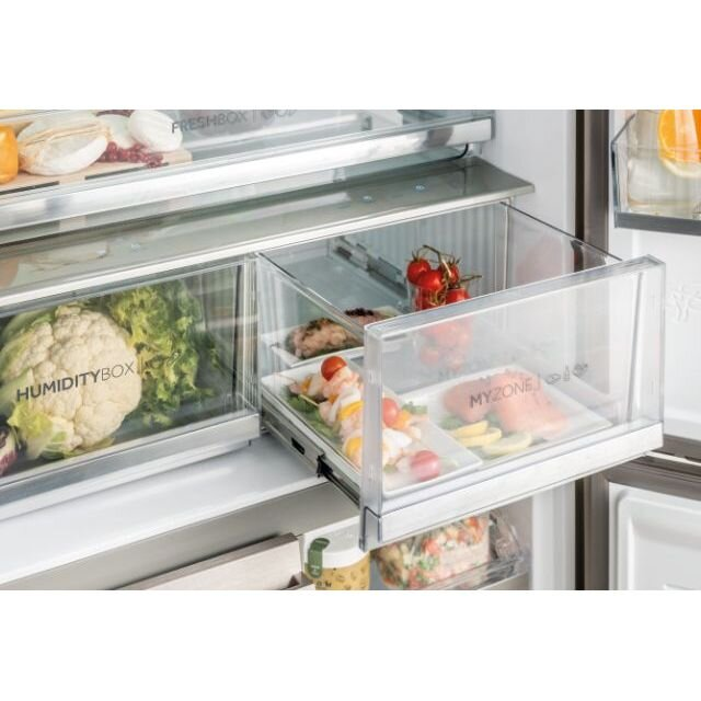 Otwarta szuflada lodówki z jedzeniem. Widoczne warzywa, gotowe dania i surowa ryba.