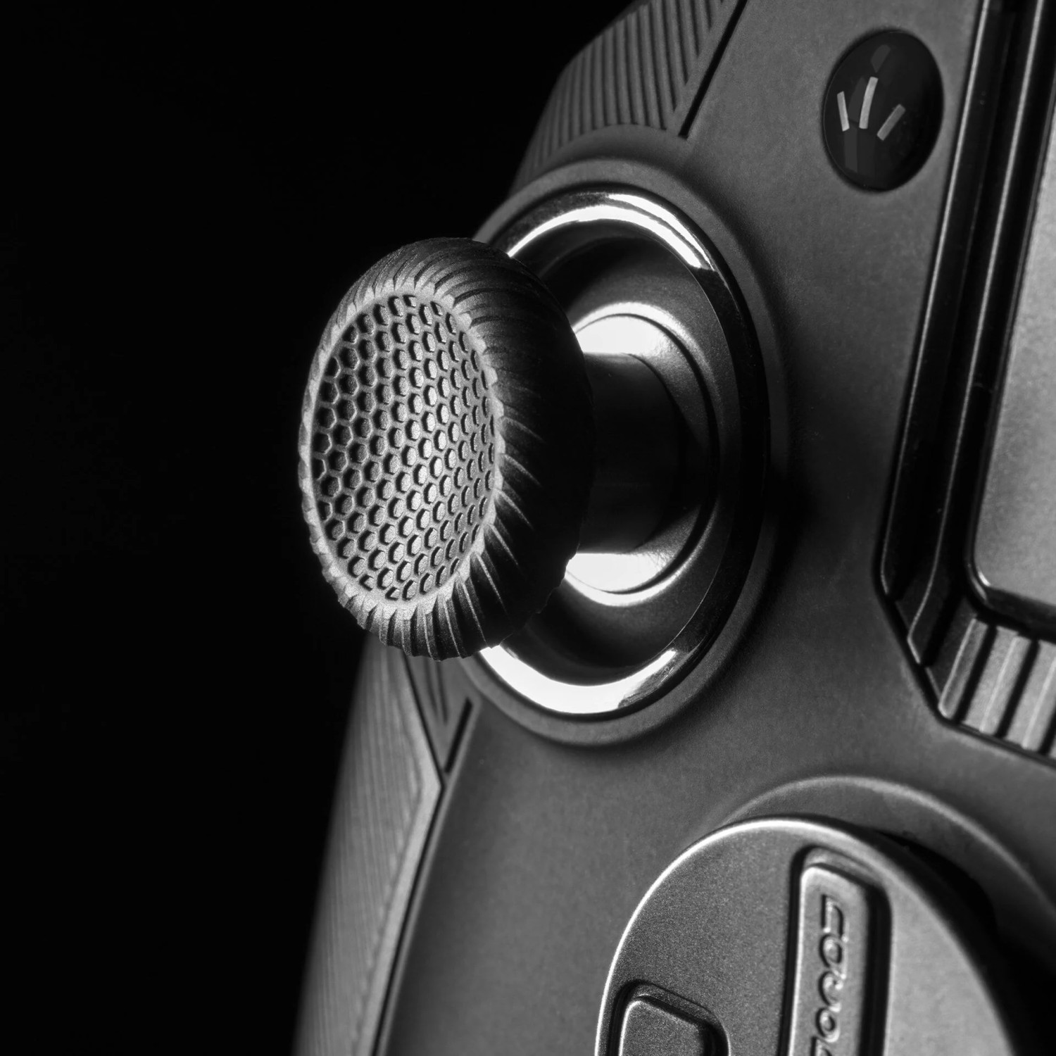 Close-up, black game controller joystick. Textured grip with a hexagonal pattern.