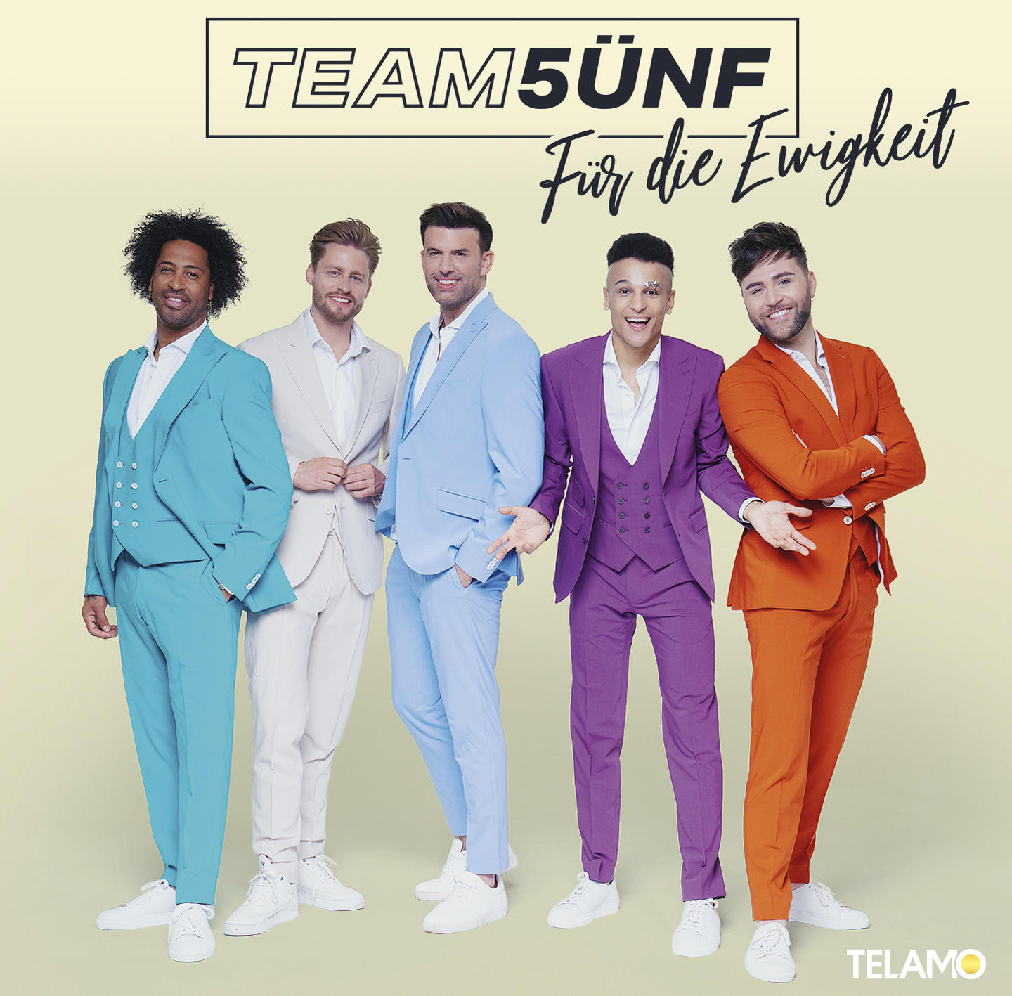 Gruppe von fünf Männern in bunten Anzügen. Sie stehen vor hellgelbem Hintergrund.