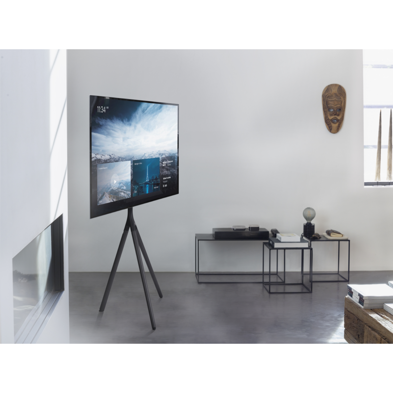 A modern living room with a TV on a tripod stand and a white wall with art.