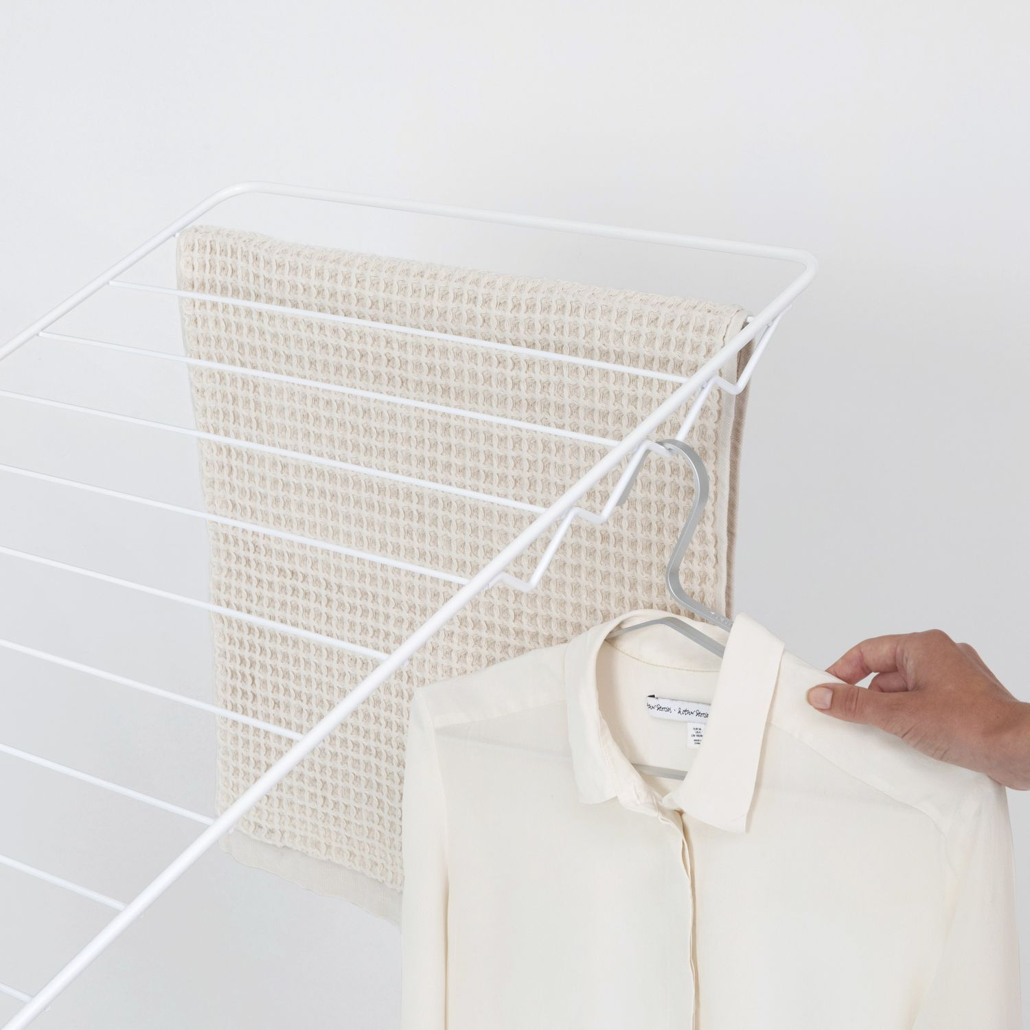 Witte droogrek met handdoek en shirt. Hand houdt shirt vast.