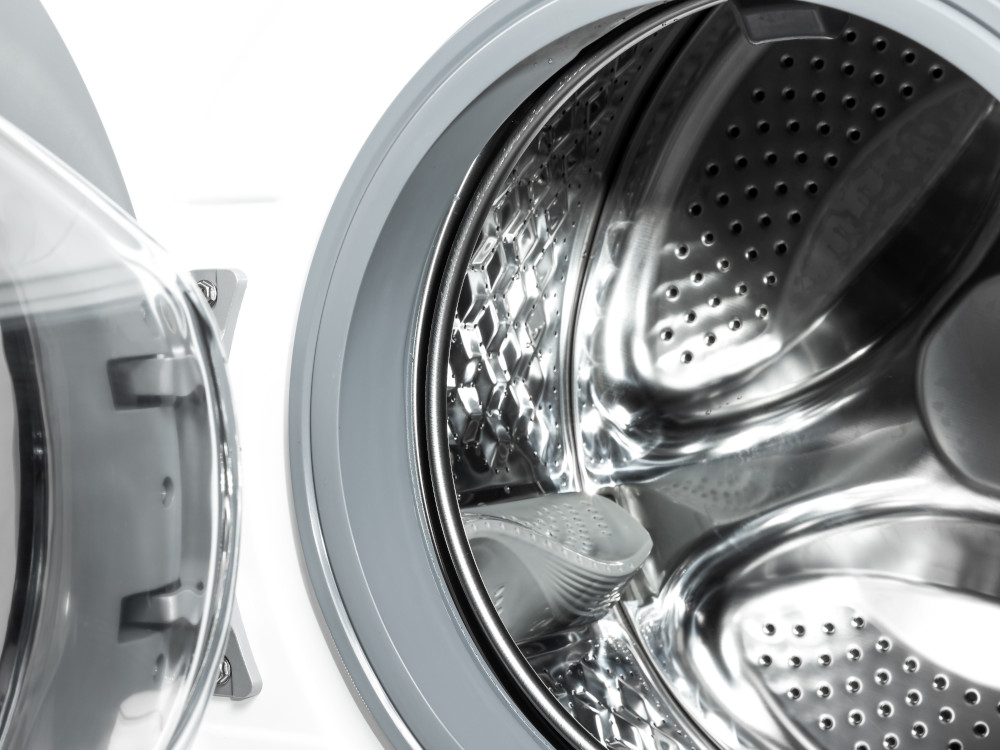 Close-up of an open washing machine drum. The interior is stainless steel with perforations.