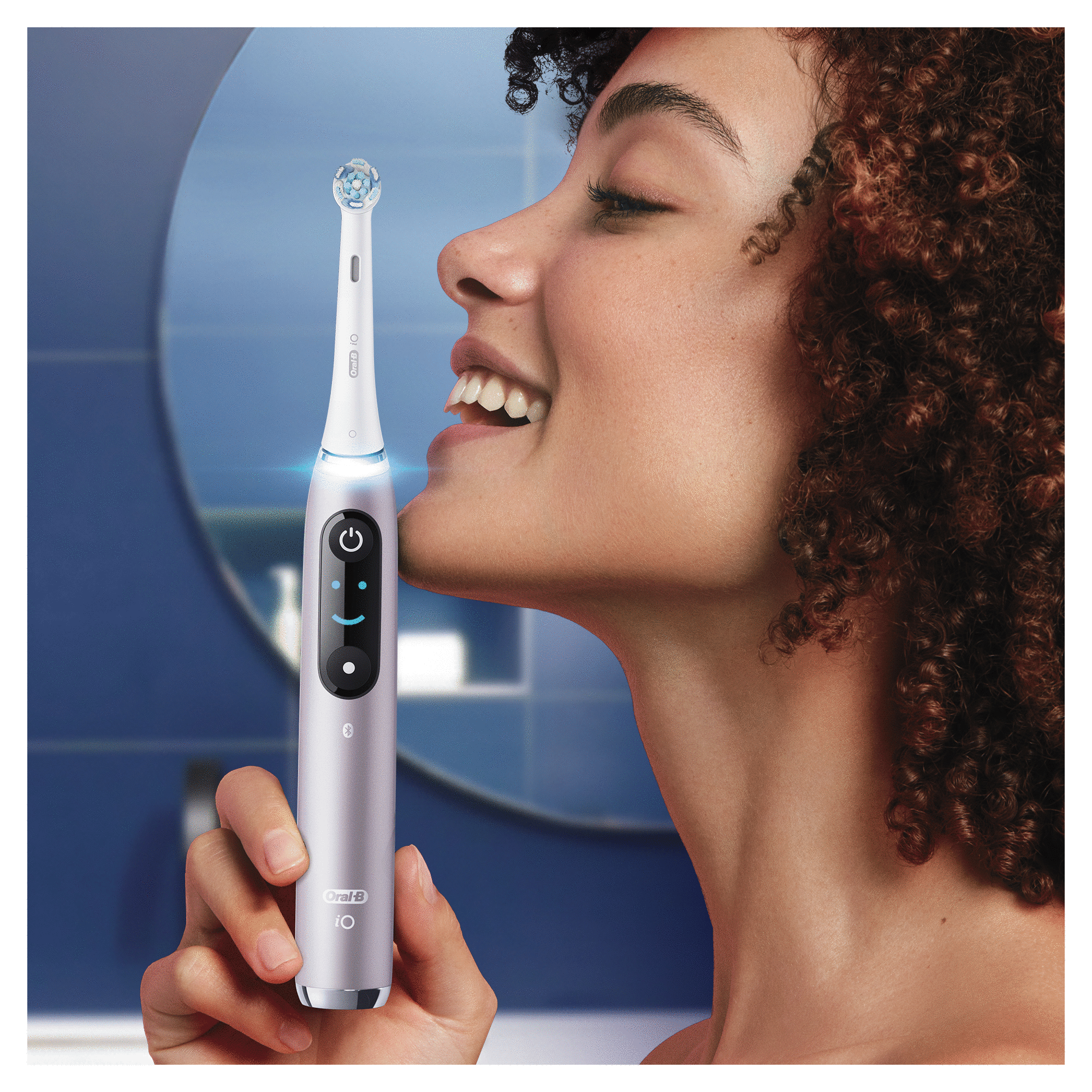 Femme utilisant une brosse à dents électrique Oral-B iO. La brosse est allumée, près de sa bouche.