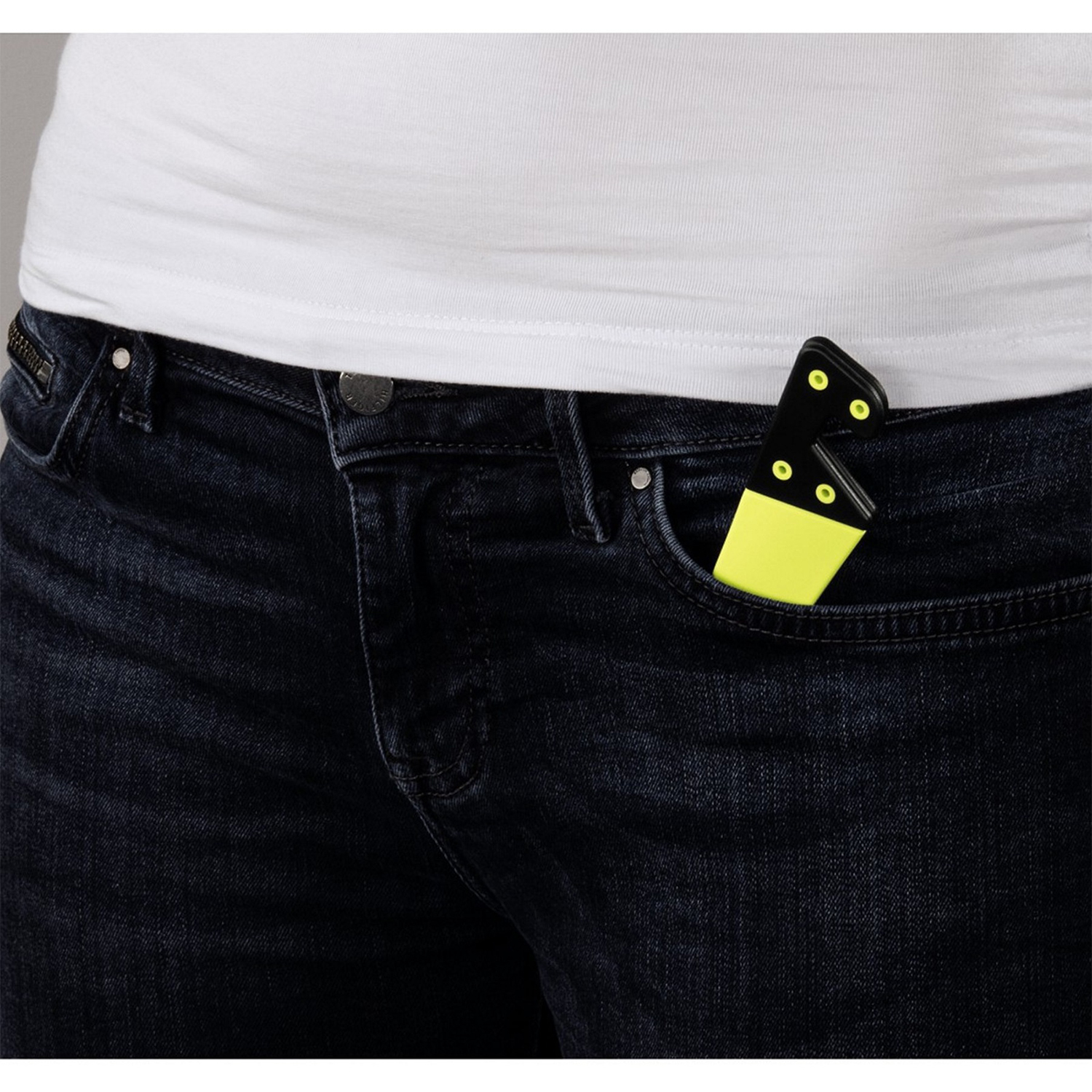 La mano di una persona in una tasca dei jeans tiene un set di domino nero e giallo.