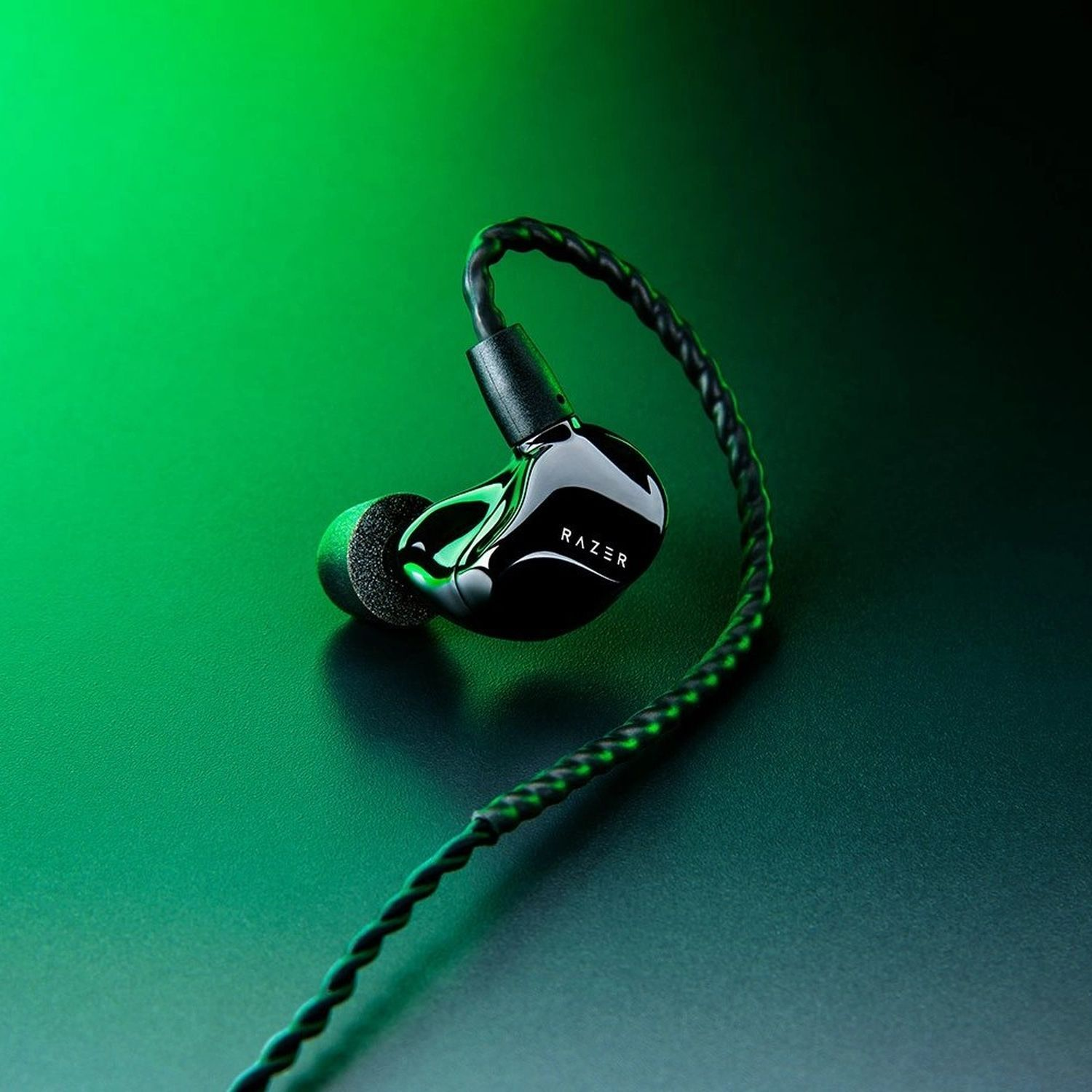 Zwarte Razer oortelefoons met een zwarte kabel. De achtergrond is een gradiënt van groen en zwart.