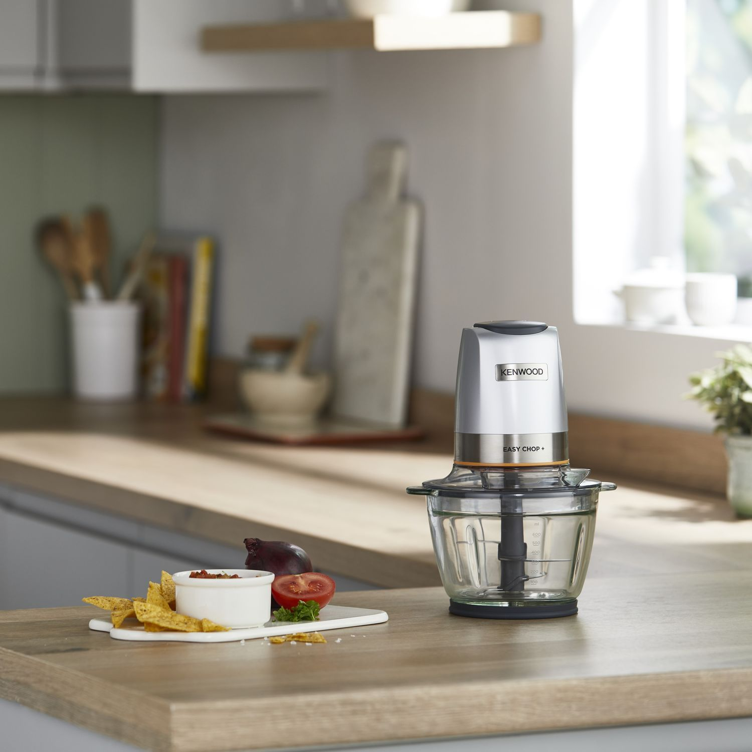 Keuken met een Kenwood food chopper, groenten en tortillachips op een houten aanrecht.