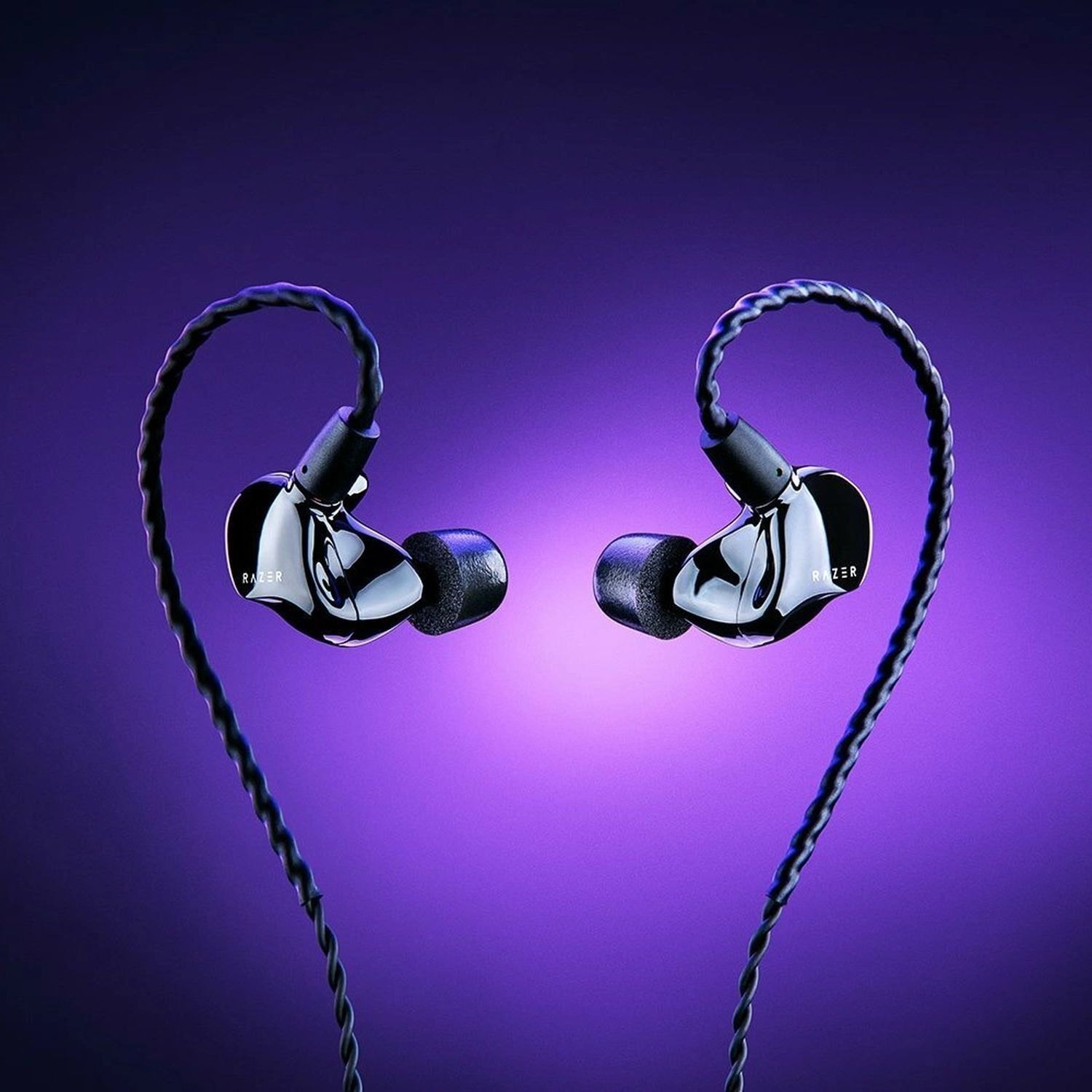 Zwarte in-ear koptelefoon met het woord 'RAZER' in het wit op de zijkant, op paarse achtergrond.